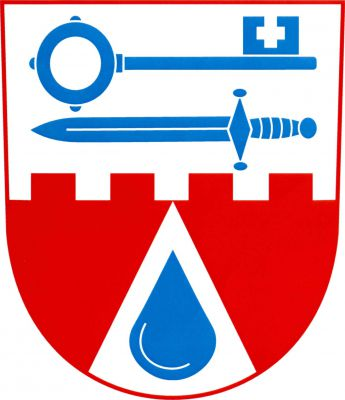 Ve stříbrno - červeně cimbuřovitě děleném štítě nahoře doleva položený klíč zuby nahoru, pod ním položený meč, obojí modré. Dole ve stříbrném zúženém hrotu modrá kapka. Znak Deštná