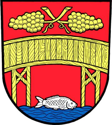 V červeném štítě s modrou vlnitou patou dřevěný most na dvou trámových podpěrách, nad mostem dva položené vinné hrozny se zkříženými stonky, vše zlaté. Pod mostem doleva plovoucí stříbrná ryba. Znak Dolní Věstonice