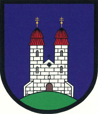 V modrém štítě na zeleném návrší stříbrné kvádrované průčelí románského kostela se dvěma věžemi s červenými střechami zakončenými zlatými makovicemi s patriarším křížem. Znak Tismice