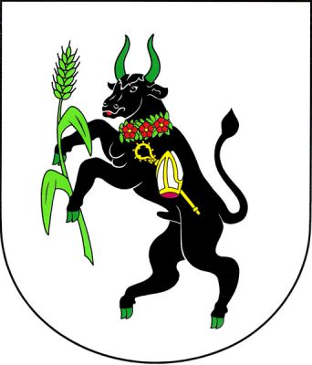 Ve stříbrném štítě vzpřímený černý býk se zelenou zbrojí a červeným jazykem, držící zelený obilný klas se dvěma listy. Býk má kolem krku zelený věnec se třemi červenými růžemi se zlatými semeníky a na boku stříbrnou, zlatě zdobenou mitru kosmo podloženou zlatou berlou. Znak Travčice